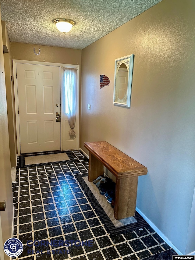 foyer featuring a textured ceiling, baseboards, and tile patterned floors