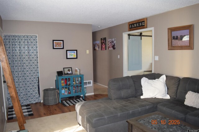 living room with wood finished floors, a barn door, and baseboards