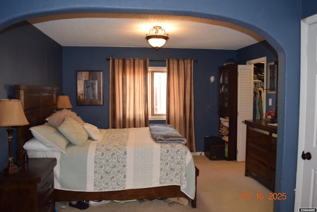 carpeted bedroom featuring arched walkways and a closet