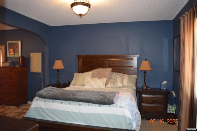 bedroom featuring arched walkways and a textured ceiling