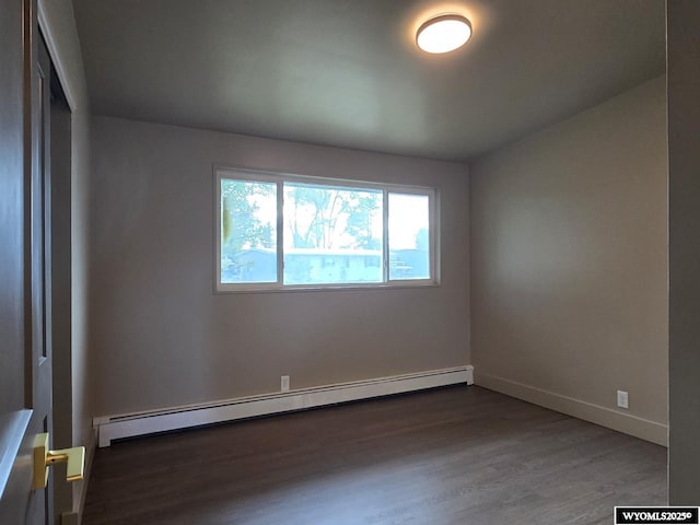empty room with a baseboard radiator, dark wood-style flooring, and baseboards