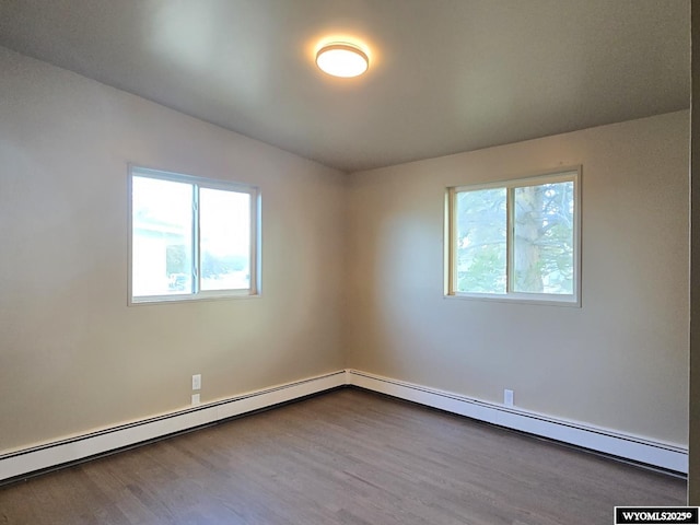 spare room featuring healthy amount of natural light, dark wood-type flooring, and baseboard heating