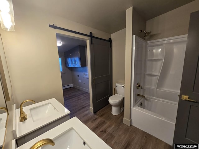bathroom featuring wood finished floors, toilet, vanity,  shower combination, and baseboard heating