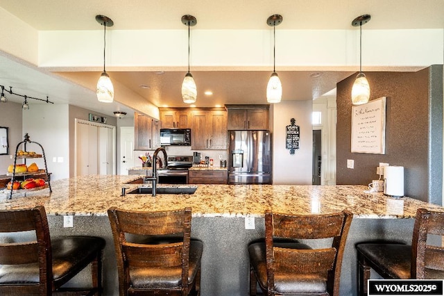 1705 N Heights Cir, Sheridan, WY 82801 - kitchen with stainless steel appliances, pendant lighting, a sink, a breakfast bar area, and light stone counters