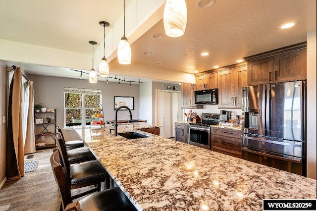 1705 N Heights Cir, Sheridan, WY 82801 - kitchen with appliances with stainless steel finishes, a sink, light stone countertops, a kitchen bar, and decorative light fixtures