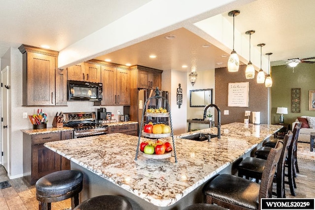 1705 N Heights Cir, Sheridan, WY 82801 - kitchen featuring stainless steel appliances, a sink, a kitchen bar, light stone counters, and recessed lighting