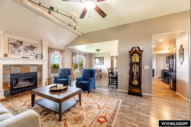 1705 N Heights Cir, Sheridan, WY 82801 - living room featuring vaulted ceiling, ceiling fan, light wood-style floors, baseboards, and a tiled fireplace
