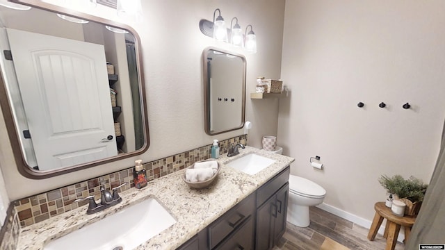 full bath with tasteful backsplash, wood finished floors, baseboards, toilet, and double vanity