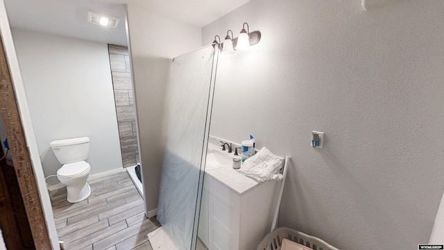 full bath with a shower stall, wood finished floors, toilet, and a sink