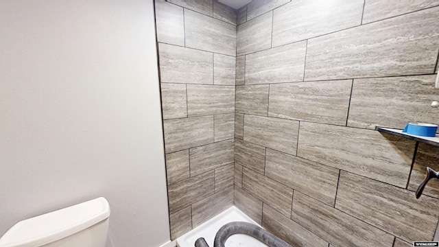 full bath featuring toilet and a tile shower