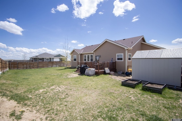 rear view of property with a shed, an outdoor structure, a deck, and a garden