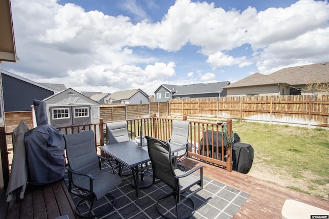 wooden terrace with outdoor dining space, a storage unit, an outdoor structure, and a residential view