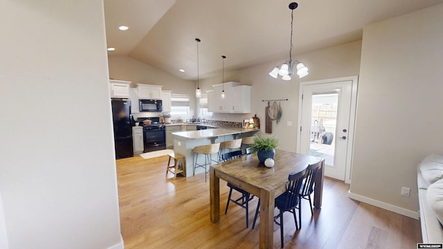 dining area with healthy amount of natural light, light wood finished floors, lofted ceiling, a chandelier, and baseboards