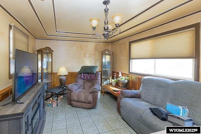 508 Sidney St, Rock Springs, WY 82901 - living room with light tile patterned flooring, a chandelier, wainscoting, a raised ceiling, and wooden walls