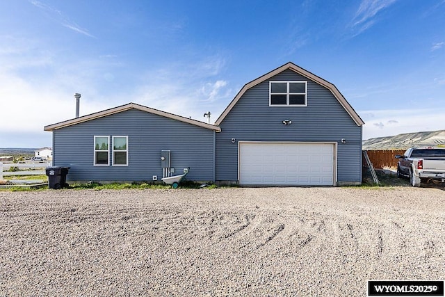 15 Greve Cir, Rock Springs, WY 82901 - view of side of home featuring a gambrel roof, a garage, gravel driveway, and fence