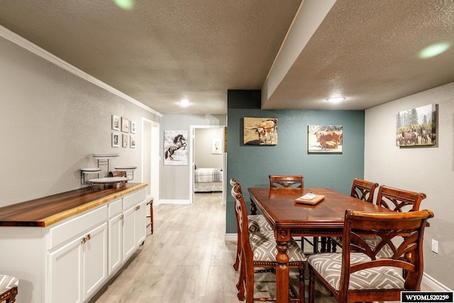 750 N Adams Ave, Buffalo, WY 82834 - dining space featuring a textured ceiling, light wood finished floors, a textured wall, baseboards, and ornamental molding