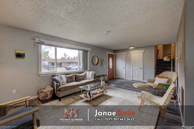 living room with a textured ceiling, stairs, wood finished floors, and baseboards