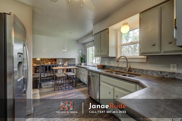 kitchen featuring stainless steel appliances, a sink, dark countertops, dark wood-style floors, and ceiling fan