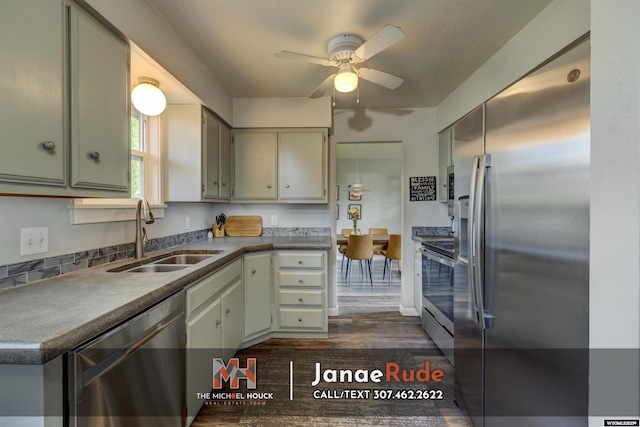 kitchen featuring appliances with stainless steel finishes, a sink, dark wood-style floors, ceiling fan, and dark countertops