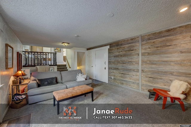 living area featuring wood walls, carpet flooring, a textured ceiling, and stairway