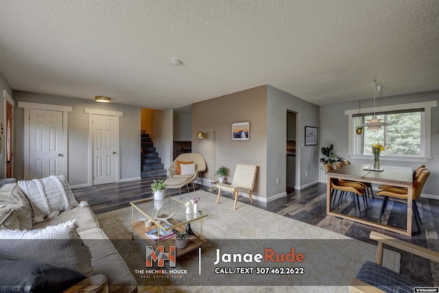 living area featuring wood finished floors, a textured ceiling, stairway, and baseboards