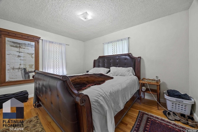 bedroom featuring a textured ceiling, wood finished floors, and baseboards