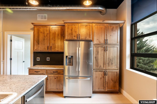 1030 N Main St, Sheridan, WY 82801 - kitchen with appliances with stainless steel finishes, brown cabinets, light wood-type flooring, and plenty of natural light