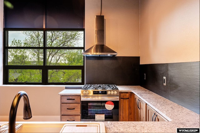 1030 N Main St, Sheridan, WY 82801 - kitchen with gas range, wall chimney exhaust hood, light countertops, and brown cabinetry