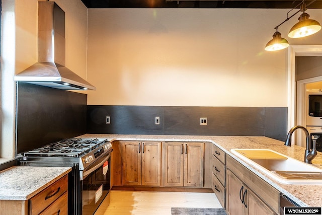 1030 N Main St, Sheridan, WY 82801 - kitchen with stainless steel gas stove, a sink, wall chimney exhaust hood, light wood-style flooring, and brown cabinetry