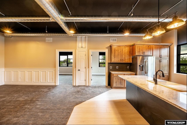 1030 N Main St, Sheridan, WY 82801 - kitchen featuring stainless steel fridge, brown cabinets, decorative light fixtures, and healthy amount of natural light