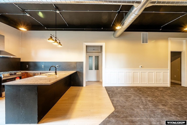 1030 N Main St, Sheridan, WY 82801 - kitchen featuring stainless steel gas range, a sink, a peninsula, rail lighting, and wainscoting