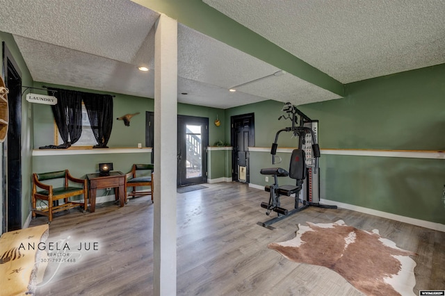 exercise area featuring a textured ceiling, wood finished floors, baseboards, and recessed lighting
