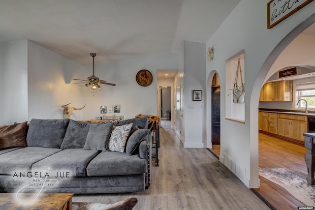 living room with a ceiling fan, wood finished floors, and arched walkways