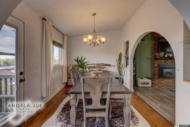 dining space featuring wood finished floors, a chandelier, and a fireplace