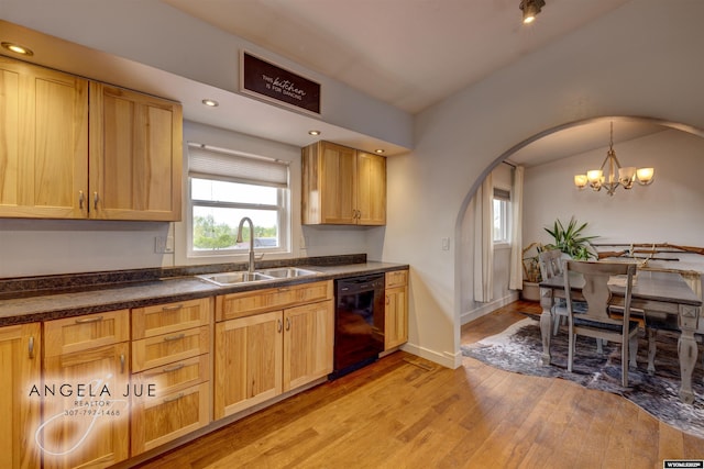 kitchen featuring black dishwasher, a sink, arched walkways, dark countertops, and light wood-style floors