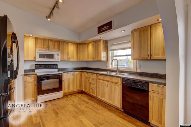 kitchen featuring black appliances, a sink, light wood finished floors, dark countertops, and lofted ceiling