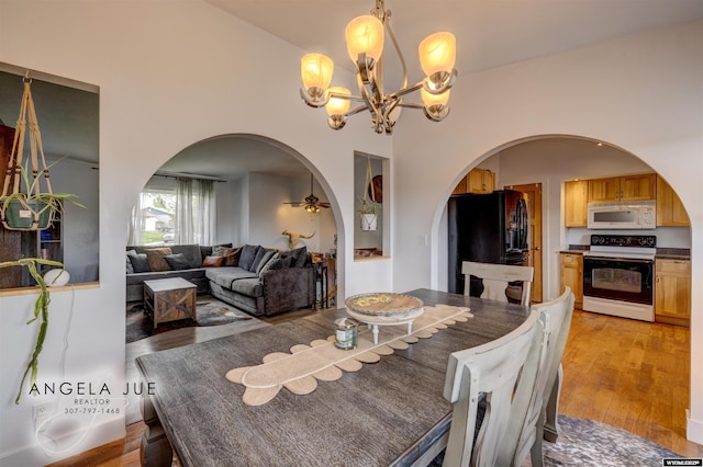 dining space featuring arched walkways, a chandelier, and light wood finished floors