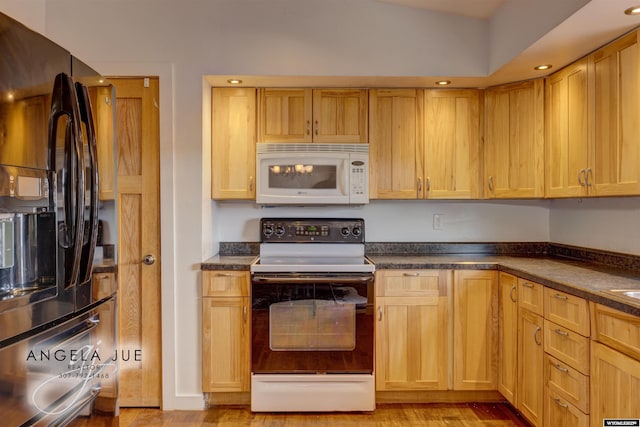 kitchen with white microwave, electric stove, freestanding refrigerator, dark countertops, and light wood-style flooring