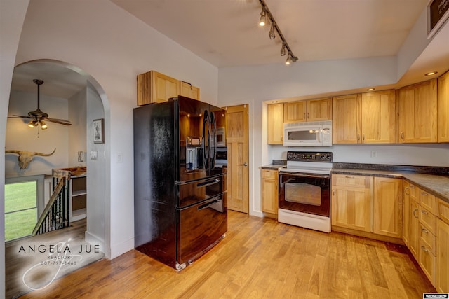 kitchen with black refrigerator with ice dispenser, range with electric stovetop, white microwave, rail lighting, and arched walkways