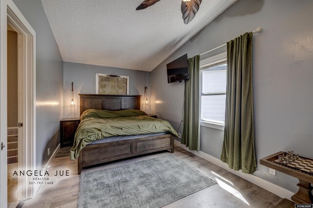 bedroom featuring a textured ceiling, lofted ceiling, and baseboards