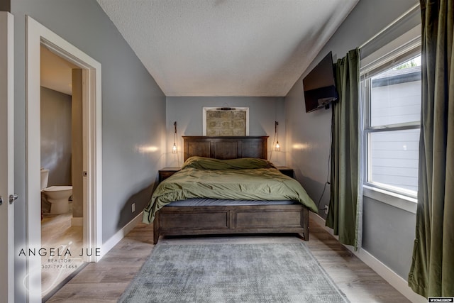 bedroom featuring wood finished floors, baseboards, and a textured ceiling