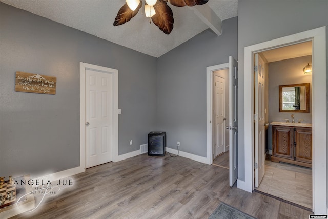 unfurnished bedroom with light wood-type flooring, connected bathroom, a sink, baseboards, and a ceiling fan
