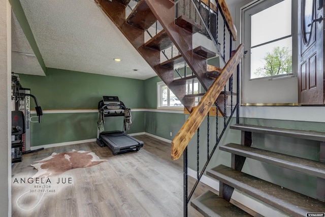 exercise area featuring wood finished floors, baseboards, a textured ceiling, and recessed lighting