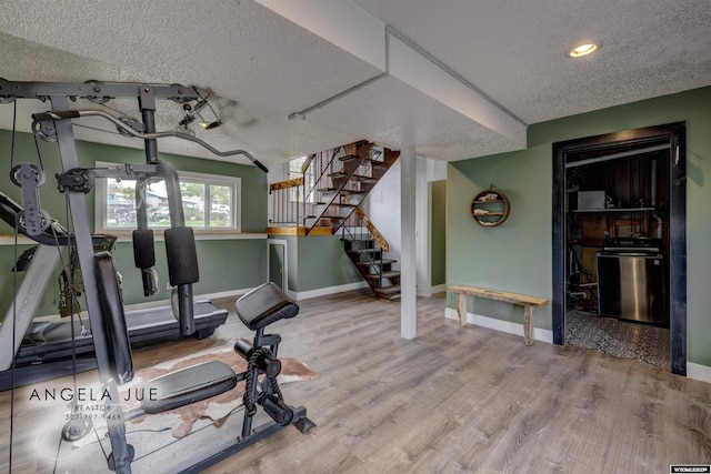 exercise room with a textured ceiling, baseboards, wood finished floors, and recessed lighting