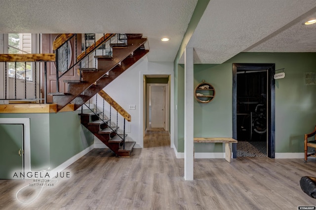 staircase with a textured ceiling, baseboards, wood finished floors, and recessed lighting