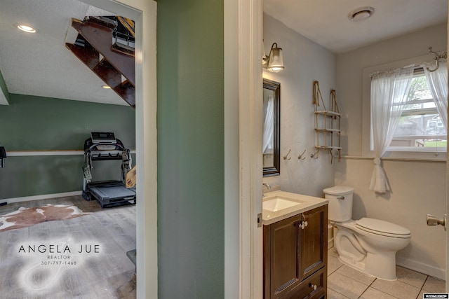 half bathroom featuring toilet, vanity, baseboards, and tile patterned flooring