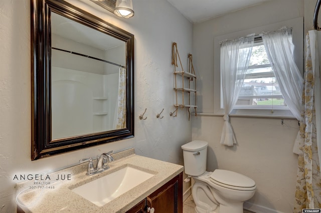 bathroom featuring toilet, baseboards, and vanity