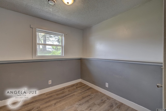 empty room with wood finished floors, a textured ceiling, and baseboards