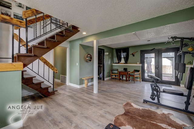 workout room featuring a textured ceiling, baseboards, wood finished floors, french doors, and recessed lighting