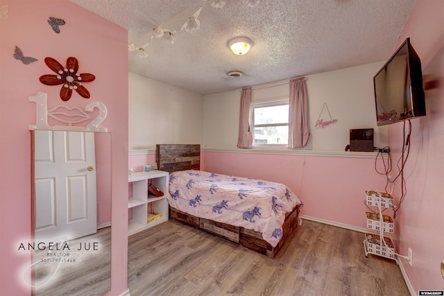 bedroom with a textured ceiling and wood finished floors